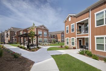 An exterior view of an apartment complex with walkways and grass